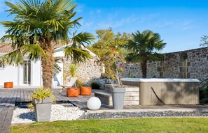 Un patio exterior moderno con pared de piedra, palmeras e hidromasaje.