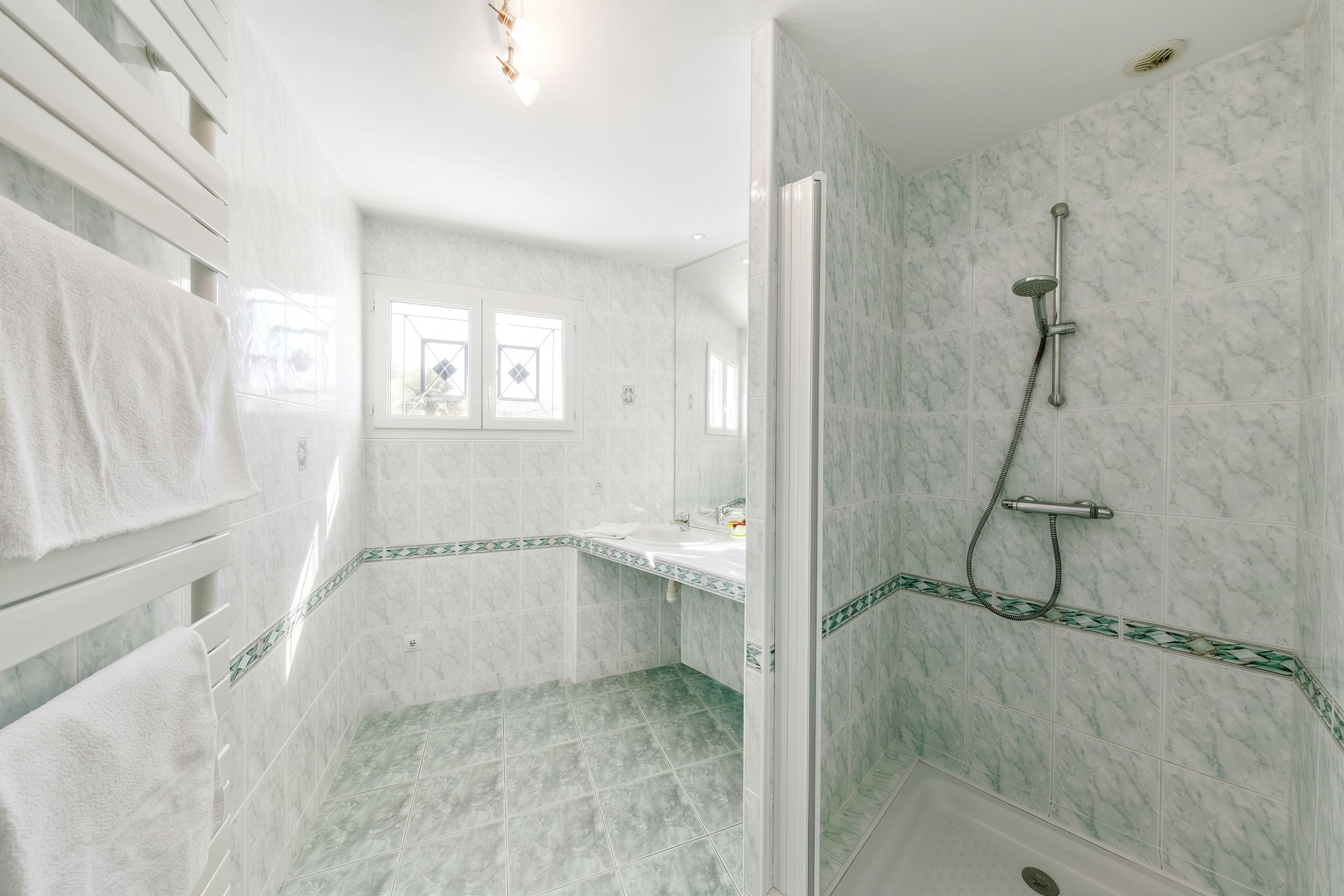 A bathroom with a shower, a sink, and a window.