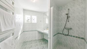 A bathroom with a shower, a sink, and a window.