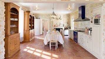 Une cuisine spacieuse avec un coin repas, dotée de meubles en bois, d’une cuisinière et d’un mur en pierre.