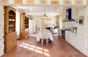 Una cocina amplia con comedor, que cuenta con armarios de madera, una estufa y una pared de piedra.