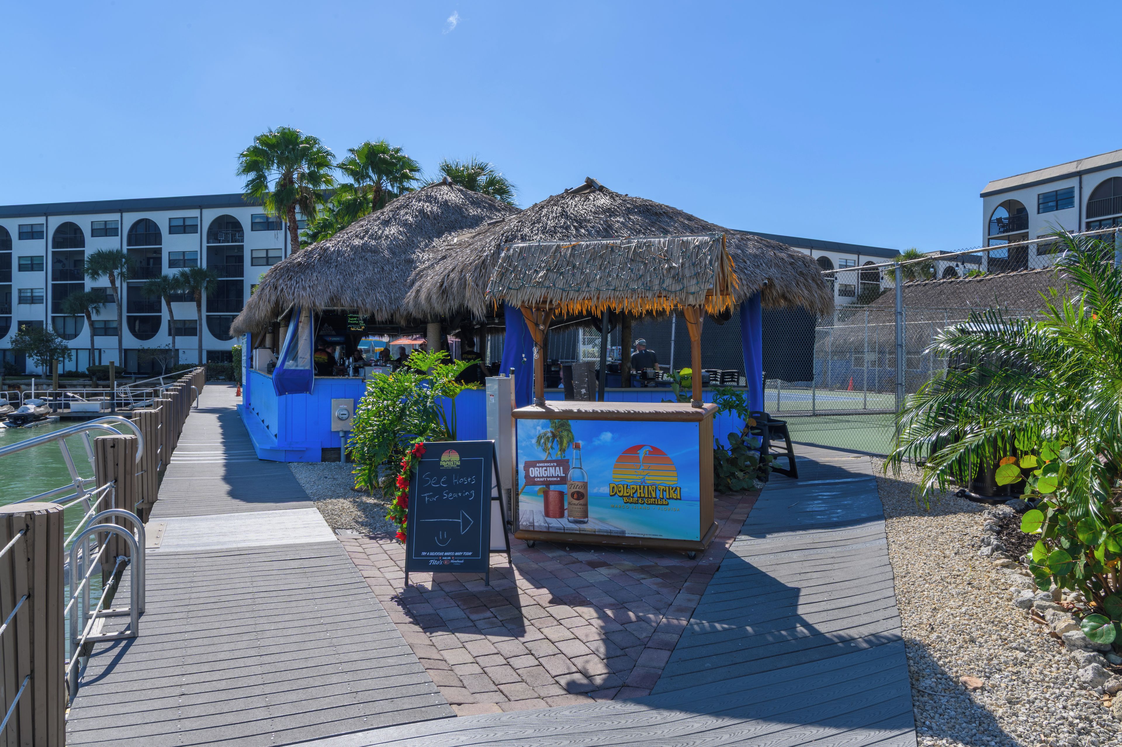 A beachfront bar with thatched roofs and a sign advertising seating.