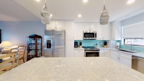 Enjoy cooking in this well-equipped kitchen with a large island, refrigerator, microwave, and oven.