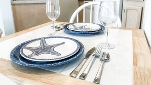 A dining table set with blue plates featuring a starfish design, silverware, and wine glasses.