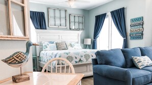 A bedroom with a bed, a blue sofa, a wooden table, and a decorative bird sculpture.