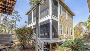 A two-story house with a porch, a covered front entrance, and a visible air conditioning unit. - Ultimate Relaxation: Resort Condo Oasis with Poolside Tiki Bar (Pensacola)