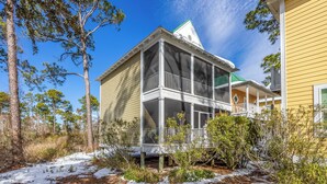 A two-story house with a porch, surrounded by trees and snow. - Ultimate Relaxation: Resort Condo Oasis with Poolside Tiki Bar (Pensacola)
