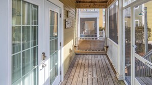 A covered wooden deck with a glass door and a bench. - Ultimate Relaxation: Resort Condo Oasis with Poolside Tiki Bar (Pensacola)