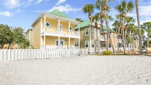 Ein Strandhotel mit einer zweistöckigen Struktur, Balkonen und einem weißen Zaun.