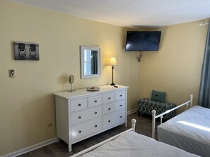 A bedroom with a bed, a dresser, a mirror, a television, and a window with curtains. - Spacious & Close to Beach- Condo E (Ocean City)