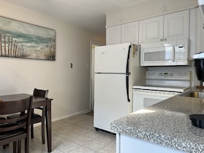 A kitchen with white cabinets, a refrigerator, a microwave, and a stove. - Spacious & Close to Beach- Condo E (Ocean City)