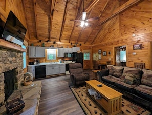 Cozy cabin interior with a comfortable couch, stone fireplace, and modern kitchen.