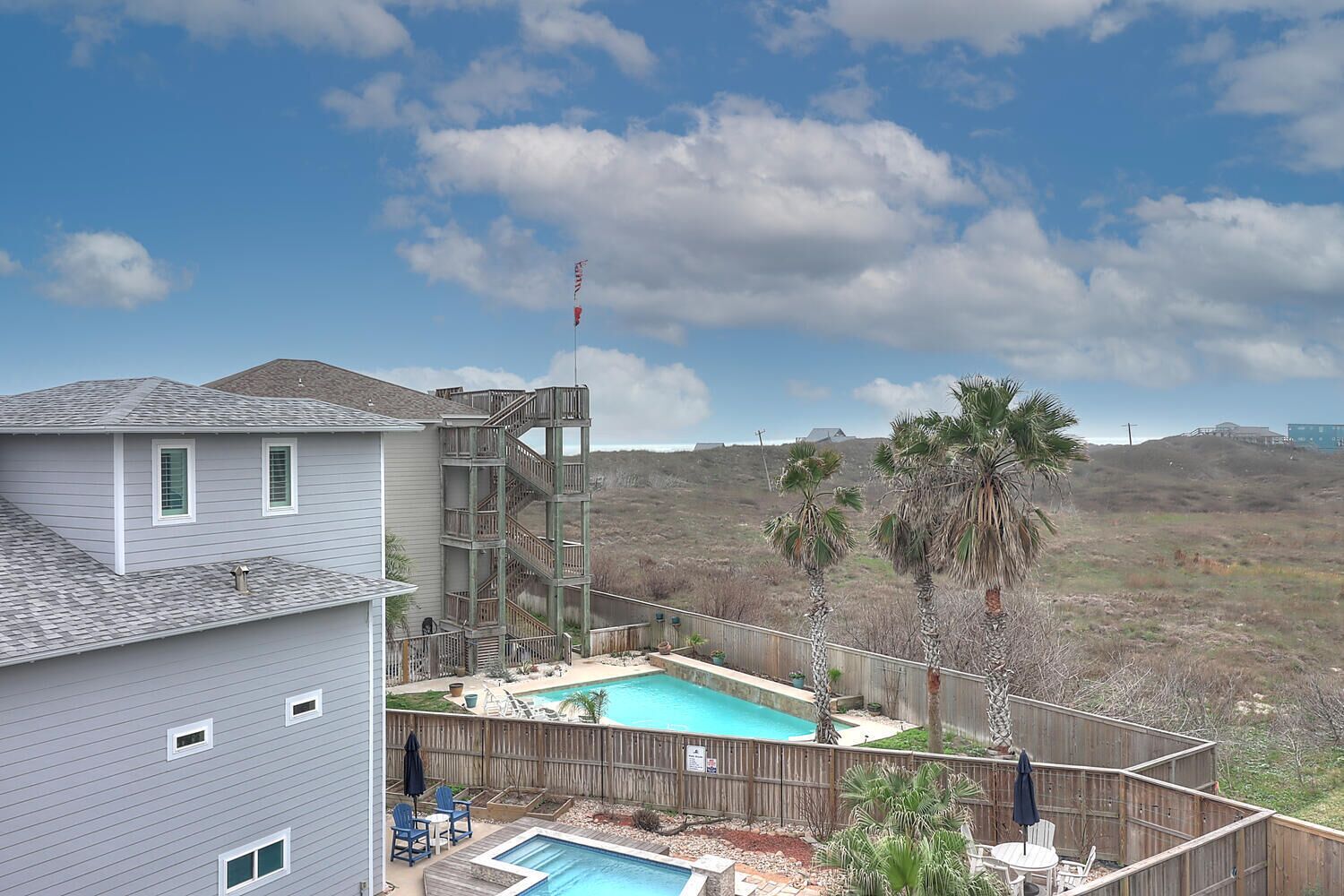 Una propiedad residencial con una casa de dos pisos, un muelle de madera, una piscina y vistas a un paisaje montañoso.