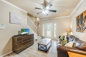 A spacious living room with a wooden coffee table, a brown leather sofa, and a ceiling fan. - Rooftop Deck with Gulf and Bay Views, Pet-Friendly, Spacious Home, Sleeps 12 (Port Aransas)