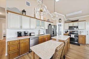 A modern kitchen with white cabinetry, stainless steel appliances, and a central island.