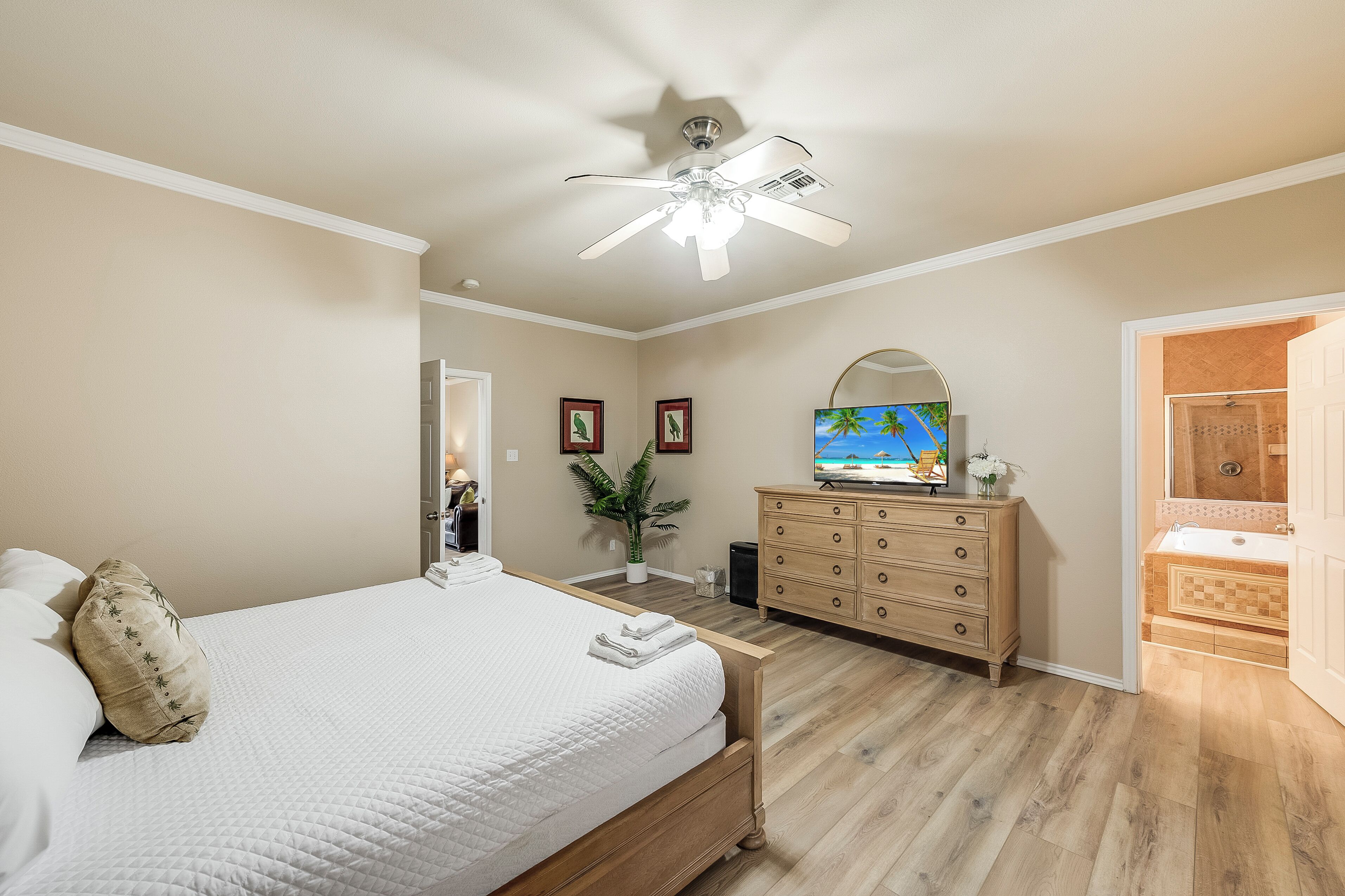 A bedroom with a bed, dresser, TV, and bathroom.