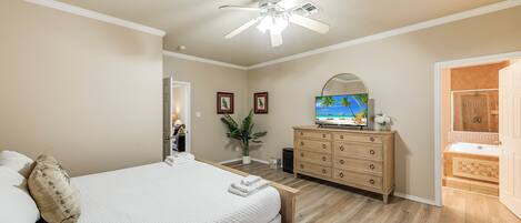 A bedroom with a bed, dresser, TV, and bathroom.