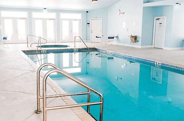 An indoor swimming pool with clear lanes, a metal safety railing, and a tiled floor. - Purple Parrot Condo Near Beach with Pool (Pensacola)