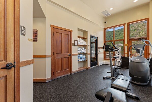 A gym with exercise equipment, a door with a sign, and a window with a view. - Freshly Updated in 2025 — Your Walk-to-Slopes Mountain Getaway! (Keystone)