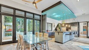 A modern kitchen with a central island, large windows, and a ceiling fan. - 17 Firethorn - HGTV "Wow-Worthy", Pool, Fire Pit (Hilton Head Island)