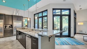 A modern kitchen with a large island, dark cabinetry, and a view to the outdoors. - 17 Firethorn - HGTV "Wow-Worthy", Pool, Fire Pit (Hilton Head Island)