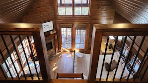 Ein Holzhaus-Innenraum mit einer Holzwindeltreppe, einem Kamin und einem Schild mit der Aufschrift Colinamornings.