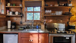 Kitchen features a sink, coffee maker, toaster, and microwave oven, with ample storage and a window above the sink.