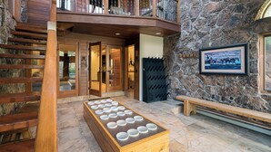 Una habitación con paredes de piedra, un banco de madera, una mesa con cuencos y un balcón con barandilla.