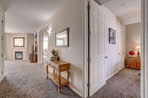 A hallway with a wooden bench, a white door, and a fireplace in the background. - Las Palmas Resort #1708 | All-Inclusive Amenities (Saint George)