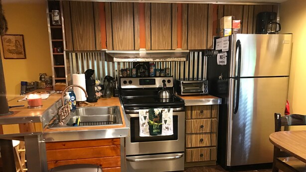 Una cocina con un refrigerador de acero inoxidable, horno empotrado, estufa, pileta y armarios de madera.