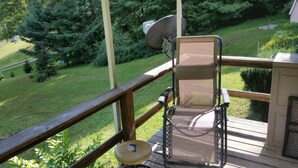 Una terraza con una silla, una antena parabólica y vistas a un paisaje verde.