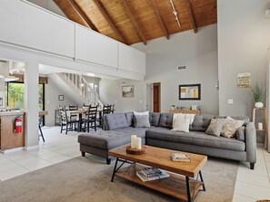 A spacious living area with a grey sectional sofa, a wooden coffee table, and a staircase leading to an upper level. - Yosemite Spacious Home Base •Near Oakhurst & Bass Lake •New Hot Tub •Secure Yard (Oakhurst)
