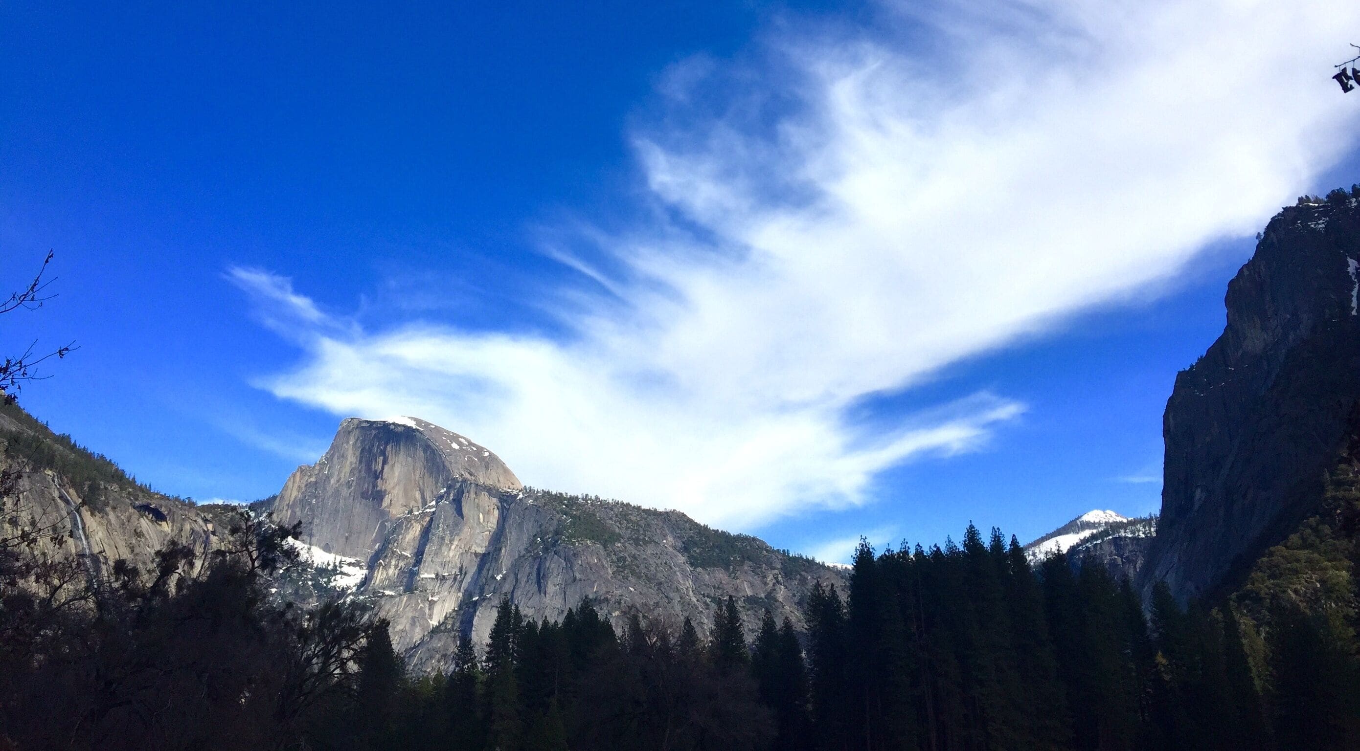 A mountain landscape with a prominent peak, dense forest, and a clear blue sky.