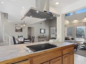 A modern kitchen with a central island, a dining area with chairs, a staircase, and a living area with a sofa. - Yosemite Spacious Home Base •Near Oakhurst & Bass Lake •New Hot Tub •Secure Yard (Oakhurst)