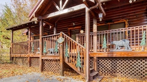 Una cabaña de madera con un porche cubierto, una escalera y un letrero que dice "The Lodge".
