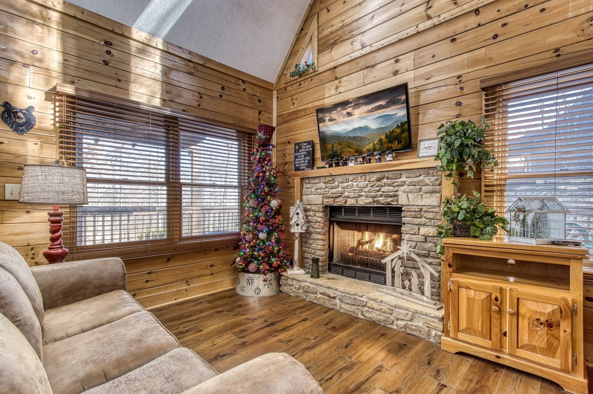 L’intérieur chaleureux d’un chalet avec des murs en bois, une cheminée en pierre et un sapin de Noël.