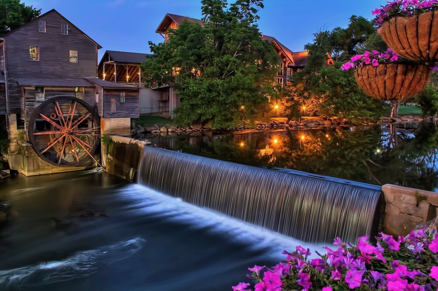 A rustic building with a large water wheel and a waterfall.