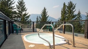 A rooftop pool with metal railings, surrounded by trees and mountains in the background. - 2BR | Powderhorn | Near Blackcomb Ski Area | Double Sided Fireplace | Rooftop Hot Tub | Parking (Whistler)