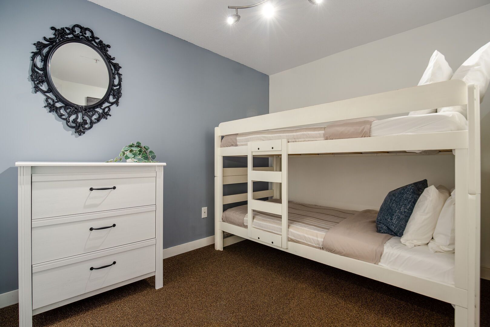 A bunk bed room with a dresser and a mirror.