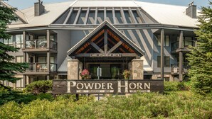 A multi-story building with a prominent entrance labeled "Powder Horn" and "4821 Spearhead Drive." - 2BR | Powderhorn | Near Blackcomb Ski Area | Double Sided Fireplace | Rooftop Hot Tub | Parking (Whistler)