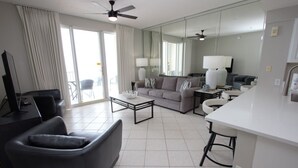 A modern hotel room with a living area, a dining area, and a balcony. - Majestic Sun 707A-1/1.5 bath condo with gulf views (Miramar Bch)