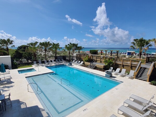 A pool area with lounge chairs and a view of the beach. - Remodeled Beachside 4025 | Spacious Condo | Beachfront | Pool + Golf Cart Included (Miramar Beach)