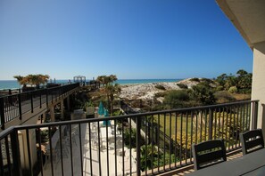A balcony with a view of the beach, outdoor seating, and a pool area. - Remodeled Beachside 4025 | Spacious Condo | Beachfront | Pool + Golf Cart Included (Miramar Beach)