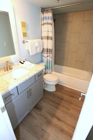 A bathroom with a sink, toilet, and bathtub. - Remodeled Beachside 4025 | Spacious Condo | Beachfront | Pool + Golf Cart Included (Miramar Beach)
