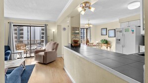 Un appartement moderne doté d’une cuisine, d’un coin repas et d’un balcon offrant une vue sur la ville.