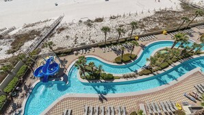 Un área de piscina con tobogán de agua, sillas de descanso y palmeras.