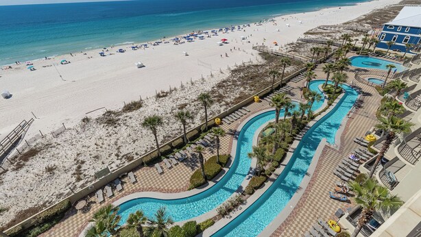 Un resort con playa, zona de piscina y un edificio de fachada azul.