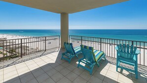Un balcón con dos sillas Adirondack azules y vista a la playa y al océano.