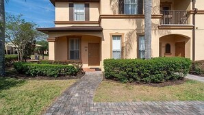 A two-story building with a brick pathway leading to the entrance, surrounded by well-maintained greenery. - Regal Palms Resort  Communal Pool, Arcade, Fitness Center & Tennis (Davenport)