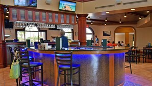 A bar area with a curved counter, bar stools, and a television mounted above. - Regal Palms Resort  Communal Pool, Arcade, Fitness Center & Tennis (Davenport)